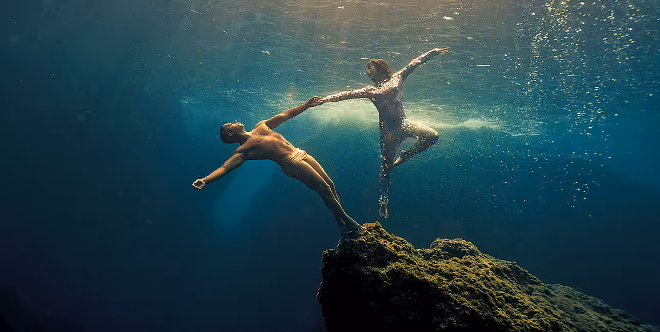 Deux plongeurs exécutent une danse gracieuse en apnée, fusionnant art et exploration sous-marine dans un ballet aquatique.