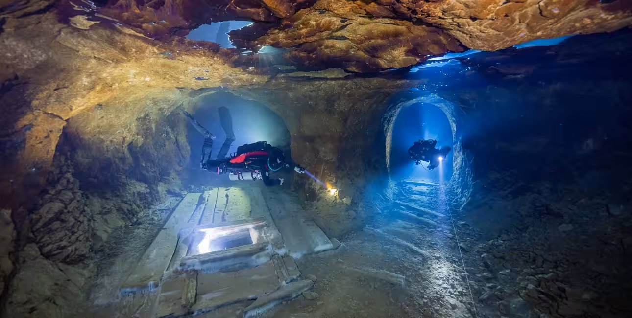 Deux plongeurs explorent une fascinante grotte sous-marine, illuminant les mystères cachés de ce monde subaquatique. #Plongée