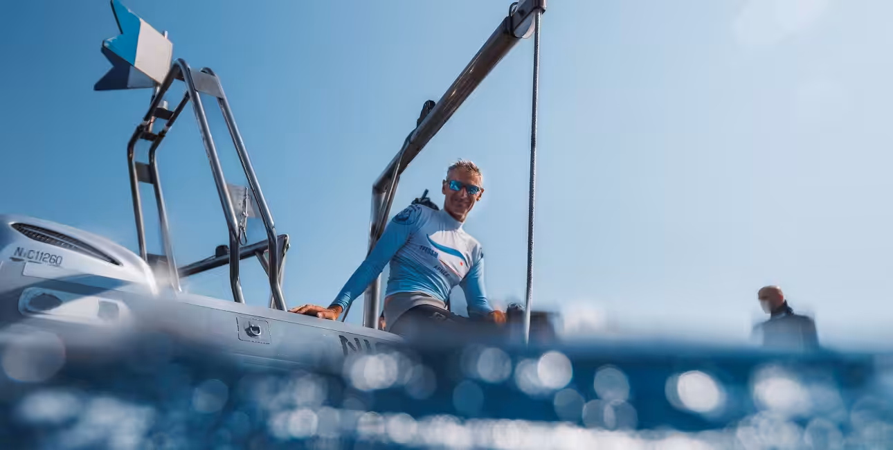 Un plongeur prépare son équipement sur un bateau sous un ciel bleu éclatant, prêt pour une aventure sous-marine exceptionn...