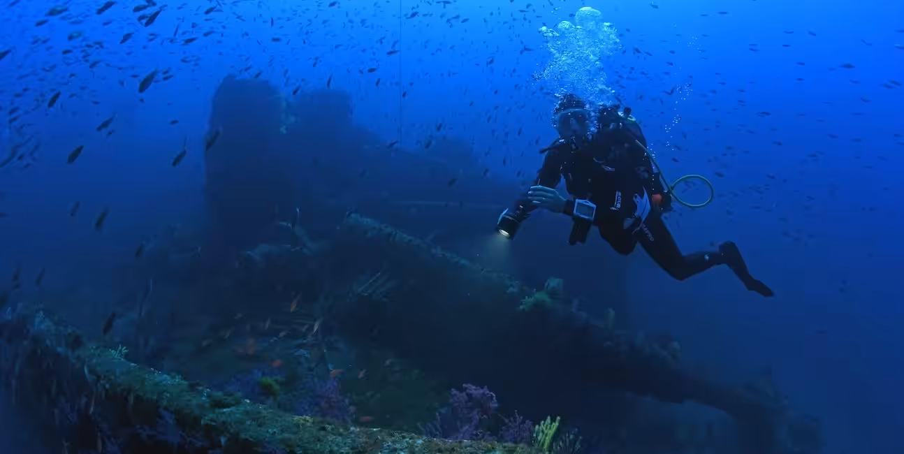 Un plongeur explore un mystérieux épave sous-marine, illuminant la biodiversité qui l'entoure dans un ballet aquatique fas...