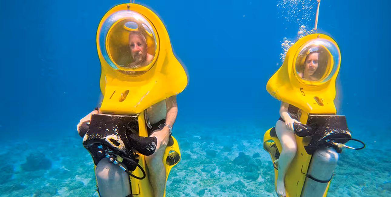Deux plongeurs explorent les fonds marins sur des scooters sous-marins, offrant une aventure unique et écologique.