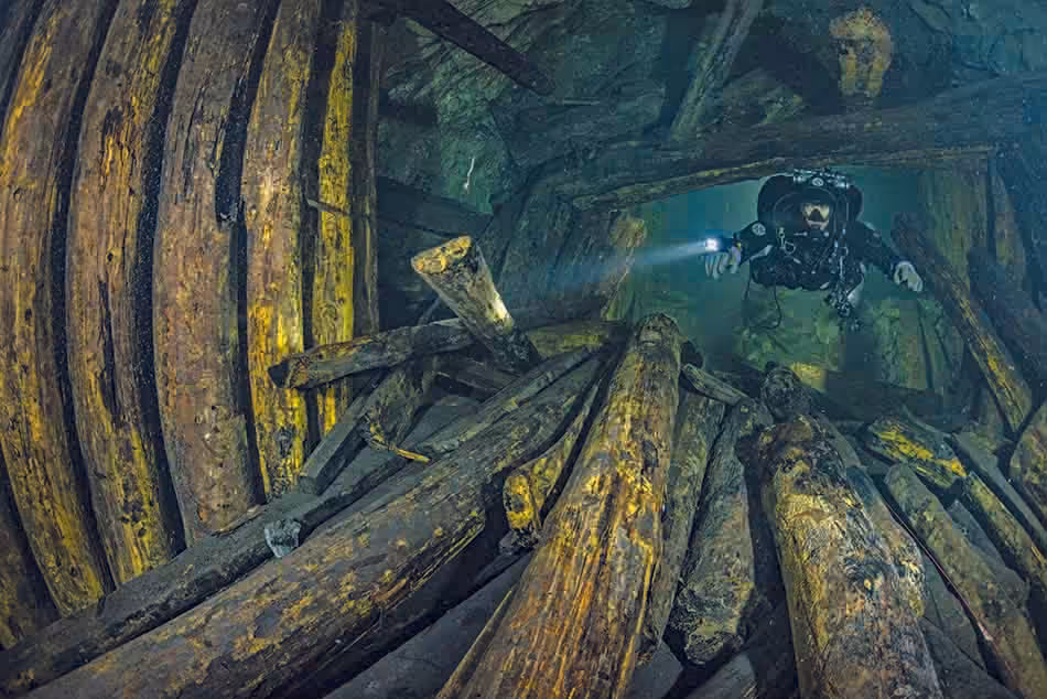 Plongée sous-marine dans une épave, révélant des structures en bois fascinantes et mystérieuses.