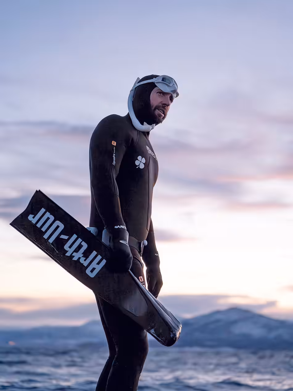 Plongeur en apnée au coucher du soleil, prêt à explorer les merveilles sous-marines.