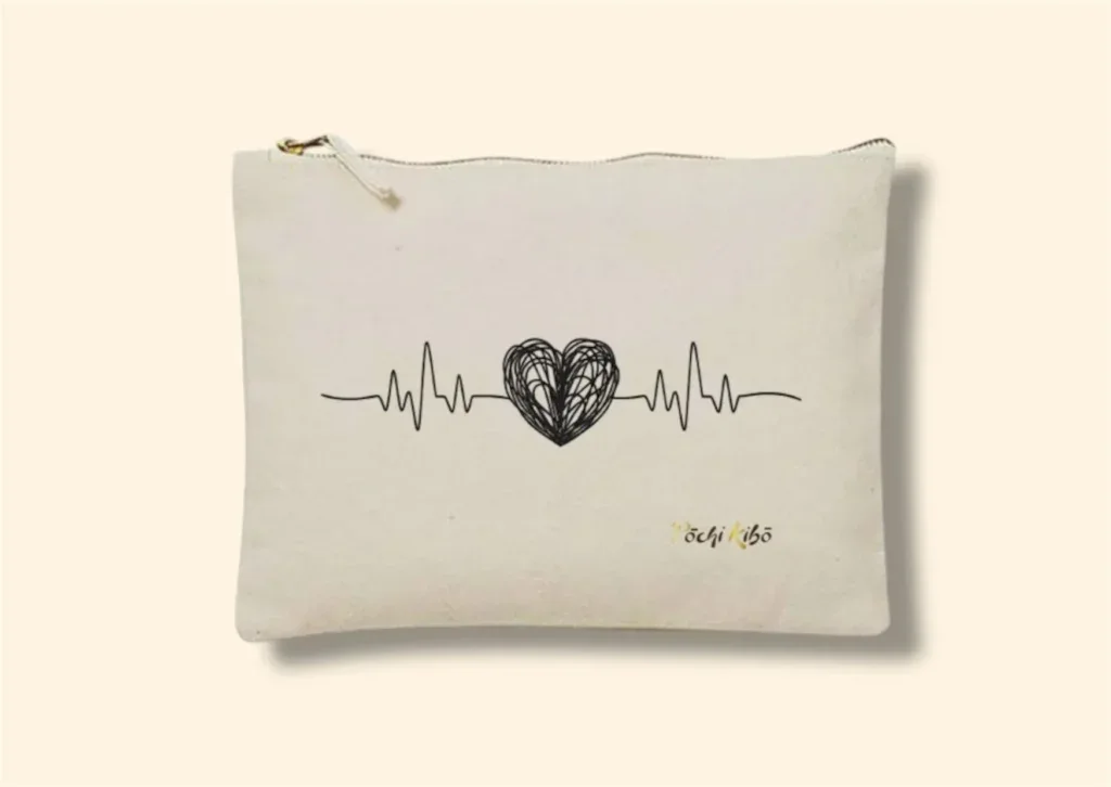 Pochette Pochi Émotions beige photographiée de face sur fond beige, tracé débutant par une ligne de fréquence cardiaque, formant un cœur noir au milieu, et reprenant la fréquence cardiaque à la fin, logo Pochi Kibo en bas à droite. Pochettes d’accompagnement et de soutien.