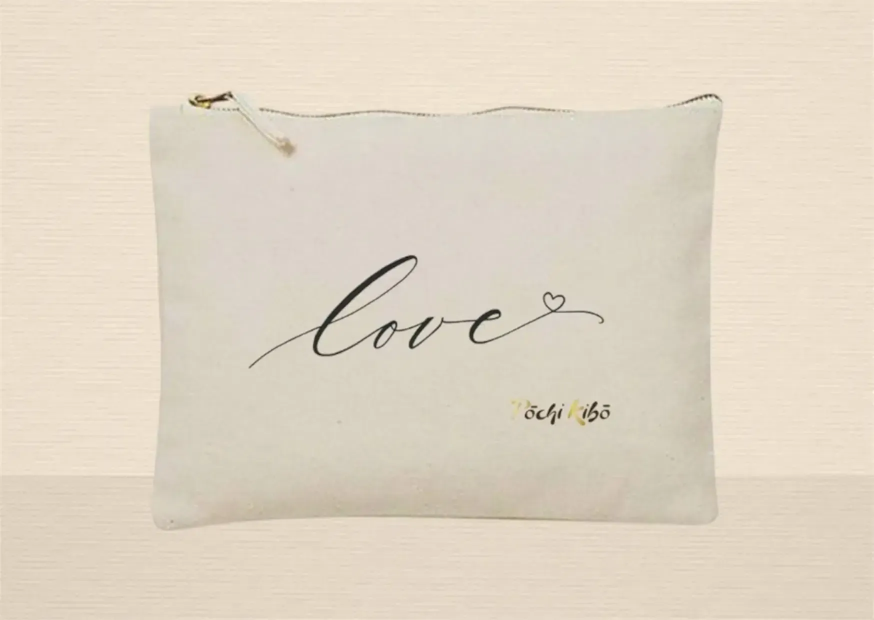 Pochette Pochi Love beige photographiée de face sur fond beige, tracé représentant le mot "Love" se terminant par un cœur, logo Pochi Kibo en bas à droite. Pochettes d’accompagnement et de soutien.