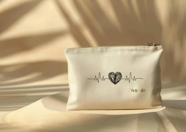 pochette-pochi-emotions Pochette Pochi Émotions avec un tracé débutant par une ligne de fréquence cardiaque, formant un cœur noir au milieu, et reprenant la fréquence cardiaque à la fin, logo Pochi Kibo en bas à droite, posée sur un dôme de sable avec fond beige assorti et ombres végétales, ambiance naturelle et douce.