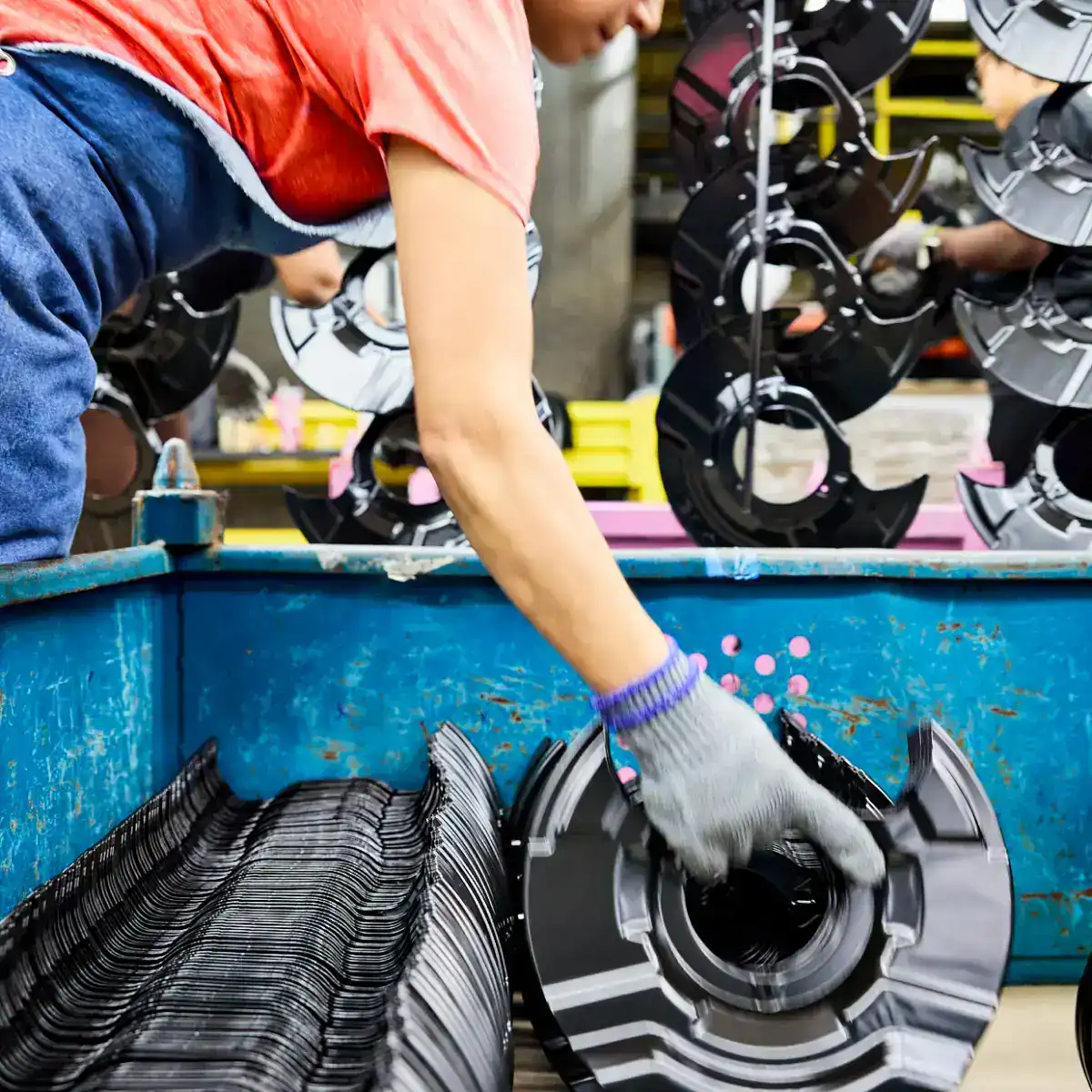 Worker inspecting helmets in a manufacturing facility.