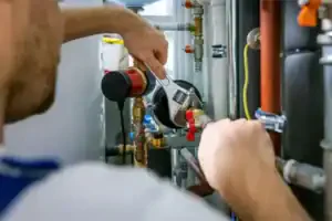 A Service Champions expert skillfully uses a wrench to adjust plumbing pipes and valves, ensuring dependable home comfort.