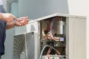 A Service Champions expert in Brea, CA carefully repairs an outdoor AC unit, ensuring safe, reliable home comfort for our neighbors.