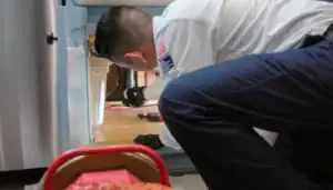 A friendly technician in Brea, CA inspects under-sink plumbing, expertly ensuring comfort and reliability for local families.