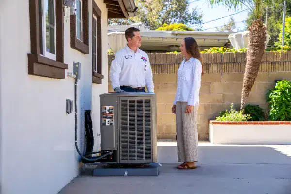 A Service Champions technician warmly discusses A/C repair solutions with a homeowner outside, ensuring dependable home comfort.