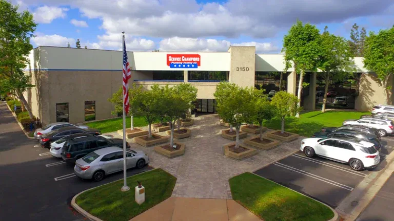 A welcoming beige office building in Brea, CA, home to trusted local HVAC experts, with reflective windows and a U.S. flag out front.