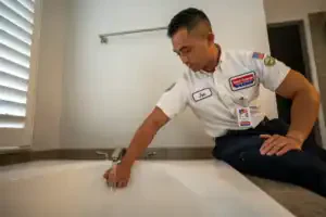 A friendly Service Champions plumber inspects a bathtub faucet, ensuring safe, dependable plumbing in a bright Brea, CA bathroom.