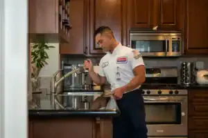 A friendly Service Champions plumber inspects a kitchen sink in a modern Brea home, providing trusted, expert plumbing service.