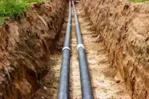 In Brea, CA, two sturdy black pipes are expertly laid in a trench—showcasing trusted local plumbing and drain service.
