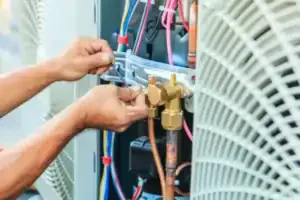 A Service Champions expert in Brea, CA carefully adjusts wiring in an AC unit, ensuring dependable comfort with trusted local care.
