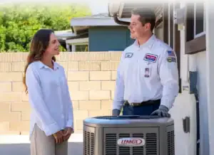 A friendly Service Champions technician chats with a homeowner by her Lennox HVAC, offering expert, dependable comfort solutions.