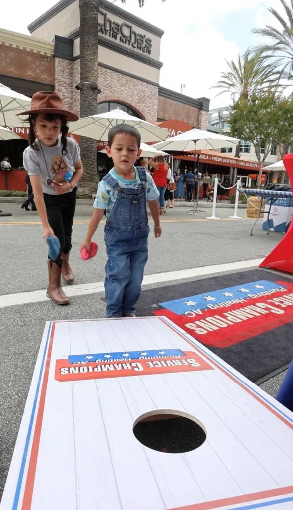 Two young children play bean bag toss on a vibrant Southern California street, reflecting our dedication to local family comfort.