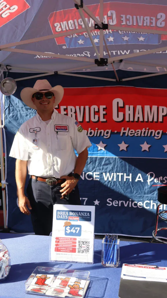 A friendly technician in uniform and cowboy hat represents Service Champions, highlighting trusted, customer-focused comfort services.