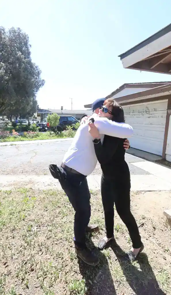 Two people share a warm hug by their driveway on a sunny day, reflecting Service Champions’ caring, local home service.