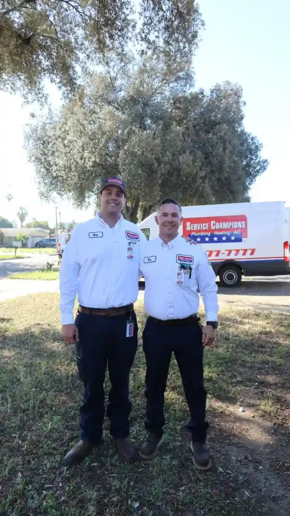 Friendly, uniformed Service Champions technicians smile outdoors by their van, ready to serve Southern California homes.