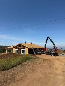 A single-story home is under construction, with dedicated workers on the roof and a crane truck carefully lifting materials nearby. Surrounded by open dirt and sparse greenery, Service Champions brings dependable home comfort expertise to this project, working alongside Homes For Our Troops to create a welcoming space for veterans. As your trusted local HVAC, plumbing, and drain professionals in Southern California, Service Champions demonstrates their ongoing commitment to helpful service and genuine care for the community.