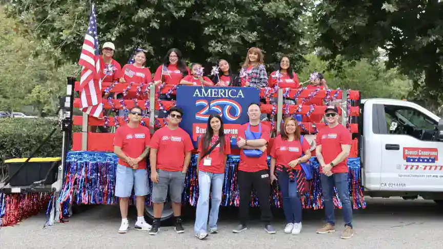 Service Champions team members, proudly wearing red shirts, gather in front of a festive truck adorned with American flags and “America 250” signage at the Mission Viejo America 250 Parade, celebrating the nation’s Semiquincentennial. Their presence highlights their dedication to serving the Southern California community as trusted, friendly experts in HVAC, plumbing, and drain services—always focused on customer comfort and reliability.