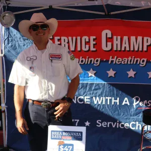 A friendly technician in uniform and cowboy hat represents Service Champions, highlighting trusted, customer-focused comfort services.