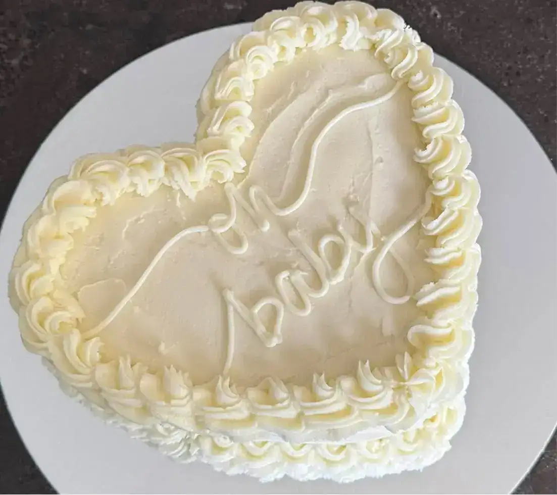 Heart-shaped cake with white frosting and 'Love' written on top.
