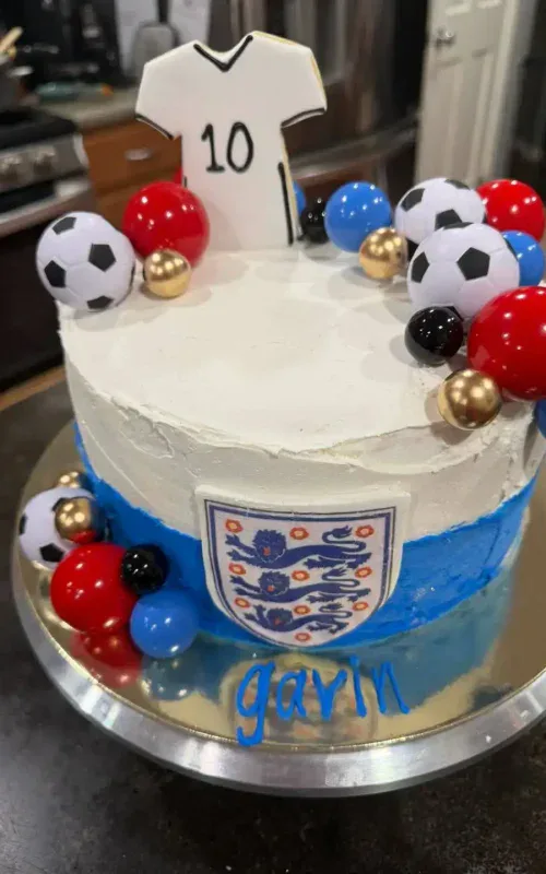 Football-themed birthday cake with England emblem and sports decorations.