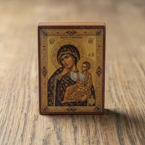 Close up of a handmade Theotokos Panagia Paramythia Orthodox wooden mounted icon on a natural wood surface.