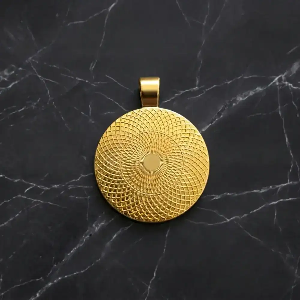Backside view of the round gold pendant tray showing its decorative filigree pattern on a black marble background.