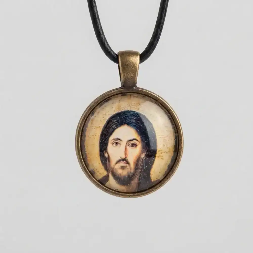 Jesus Christ Pantocrator Glass Cabochon Pendant Front View Close-up shot of a round Jesus Christ Pantocrator glass cabochon pendant with an antique bronze metal setting and black cord