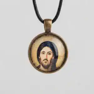 Close-up shot of a round Jesus Christ Pantocrator glass cabochon pendant with an antique bronze metal setting and black cord