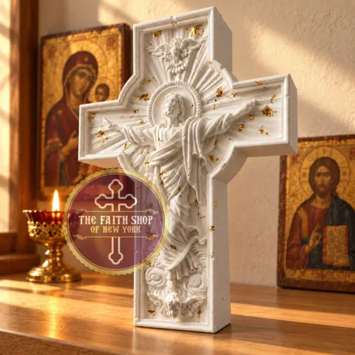 Handcrafted white ceramic resin Resurrection Standing Cross with gold leaf details displayed on a wooden surface next to traditional icons and a lit candle.
