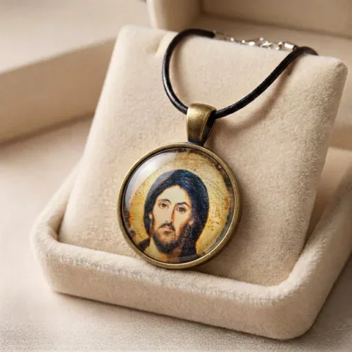 Jesus Christ Pantocrator religious glass pendant necklace arranged neatly in a beige plush velvet gift box.