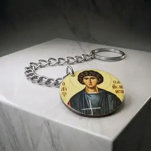 Saint Panteleimon wood mounted keychain lying flat on a white marble display block showing chain and key ring
