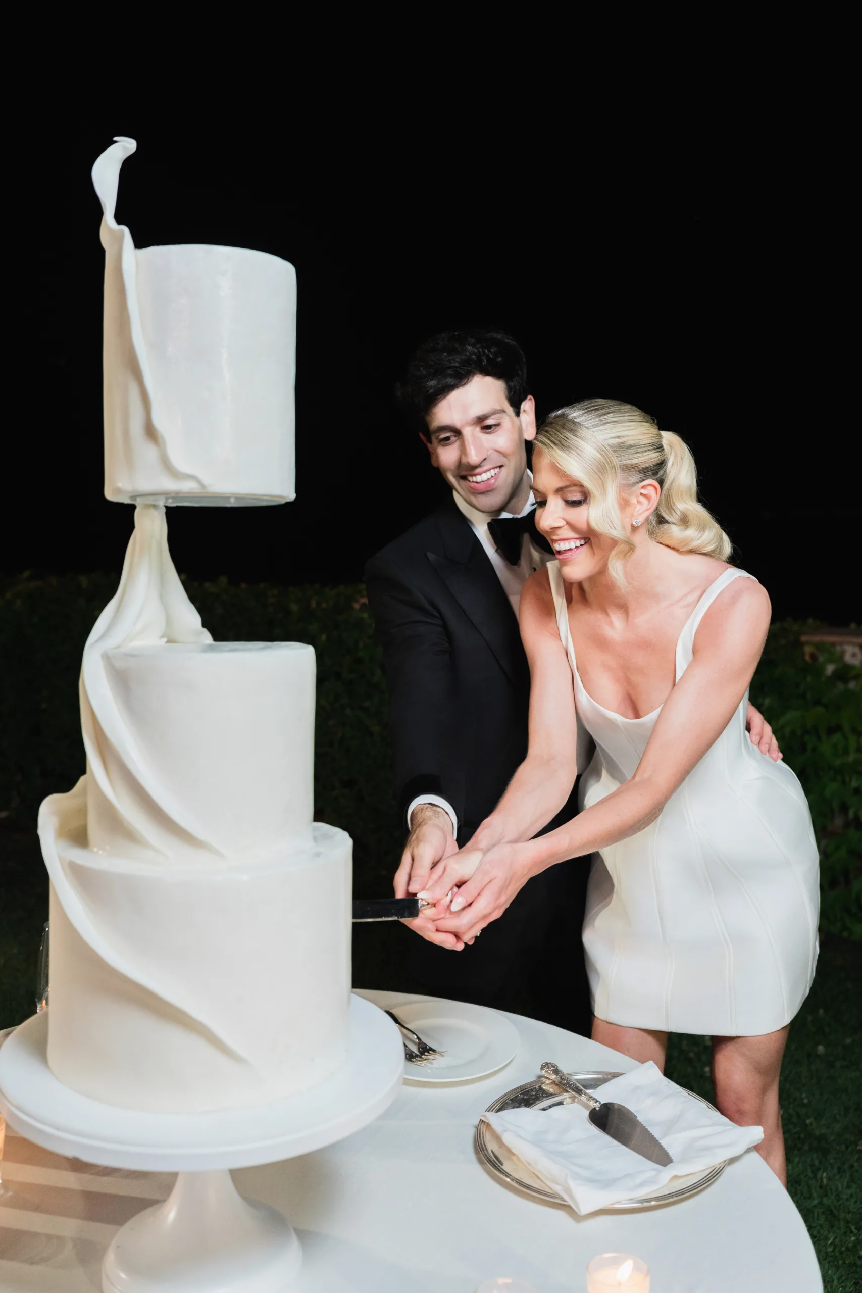 Bride and groom cutting their custom white luxury wedding cake at Villa Cimbrone, Ravello, designed by Tuscan Wedding Cakes for a destination wedding in Italy.