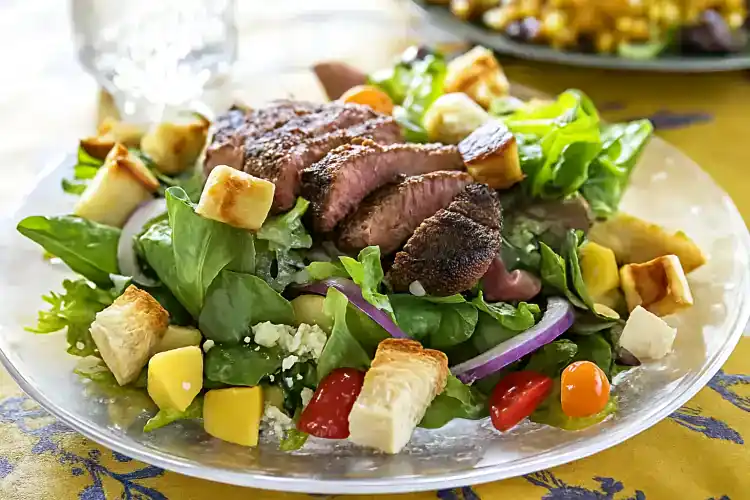 Fresh blackened steak salad with greens, cherry tomatoes, cheese, and croutons.