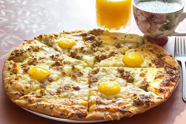 Delicious breakfast pizza topped with eggs, cheese, and bacon slices.