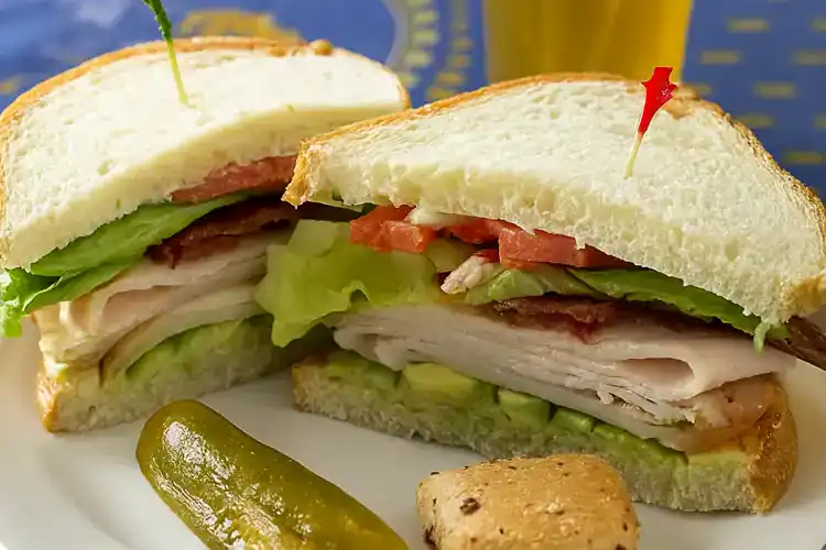 Close-up of a fresh California Club Sandwich with lettuce, tomato, turkey, and bacon.