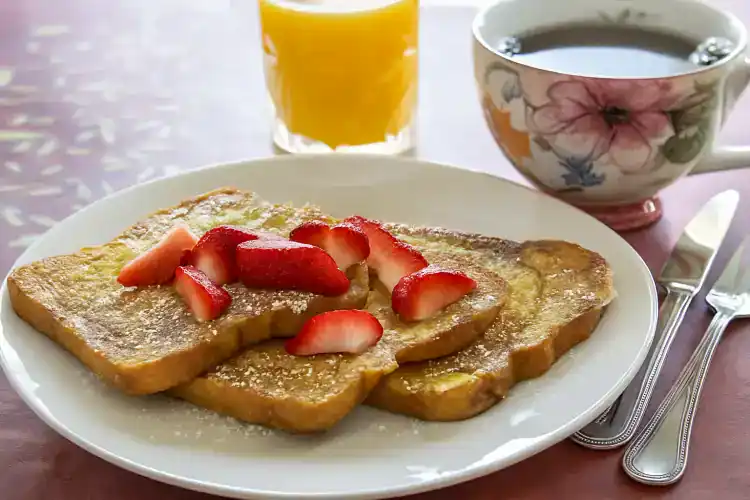French toast with strawberries, orange juice, and coffee for breakfast.