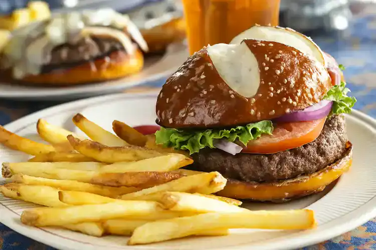 Juicy beef burger with lettuce, tomato, onion, and cheese served with fries.