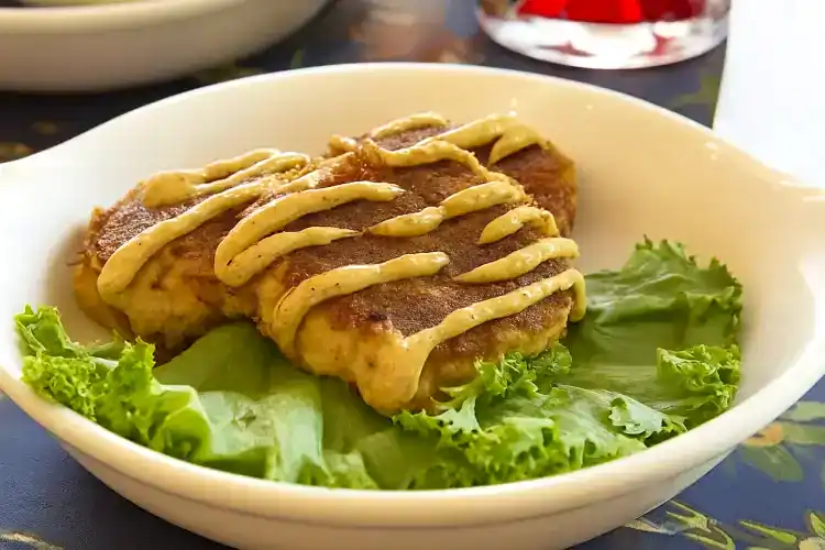 Crab cakes served on lettuce with mustard sauce drizzle.
