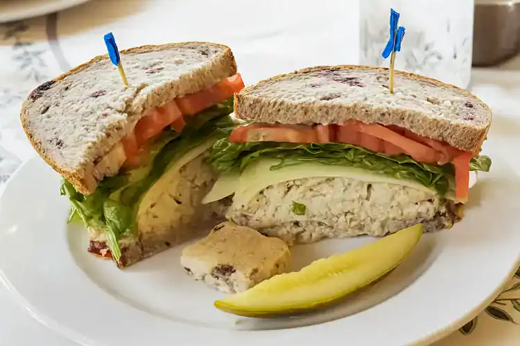 Fresh cranberry tuna sandwich with lettuce, tomato, and cheese on whole grain bread.