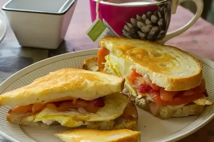 Delicious egg, provolone, and tomato sandwich on a plate.