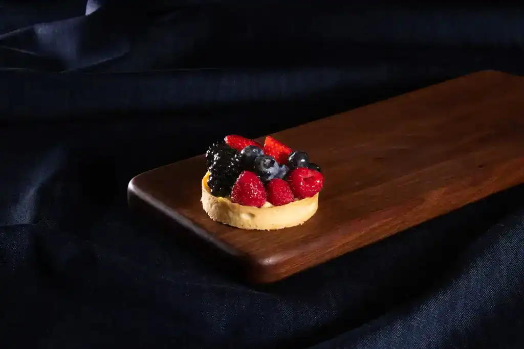 Mini fruit tart with berries on wooden board at Village Baker.