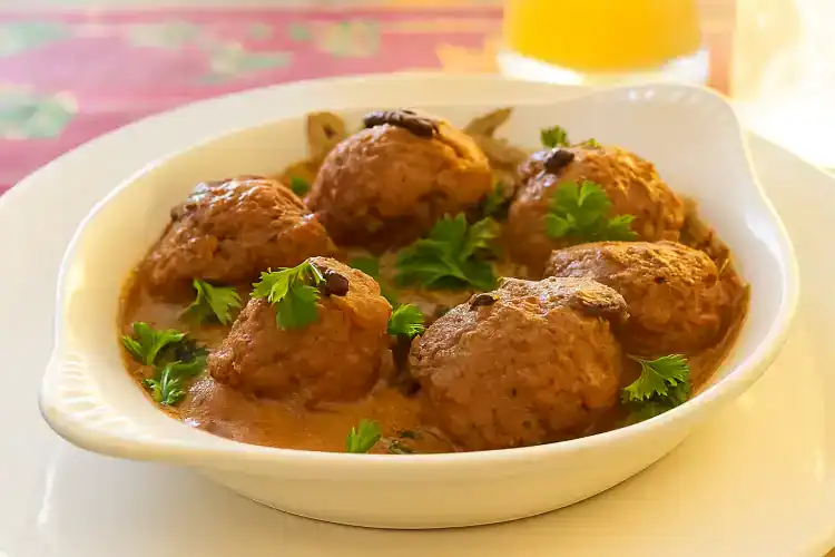Delicious German meatballs served with fresh herbs in a white dish.