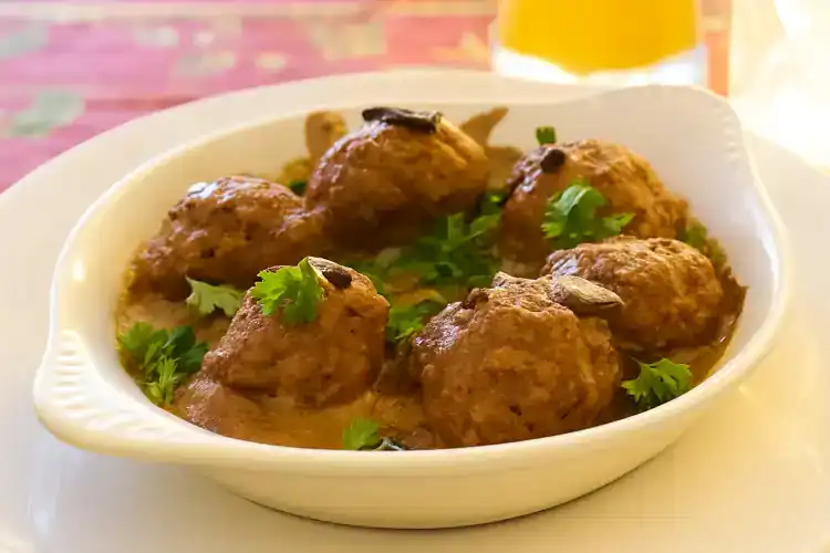 Delicious German meatballs served in a white bowl with herbs.