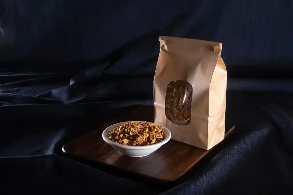 Village Baker granola in bowl with packaging on dark background.
